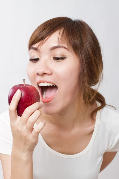 Sana mujer asiática mirando hacia arriba mientras mordiendo, comiendo manzana roja —  Fotos de Stock