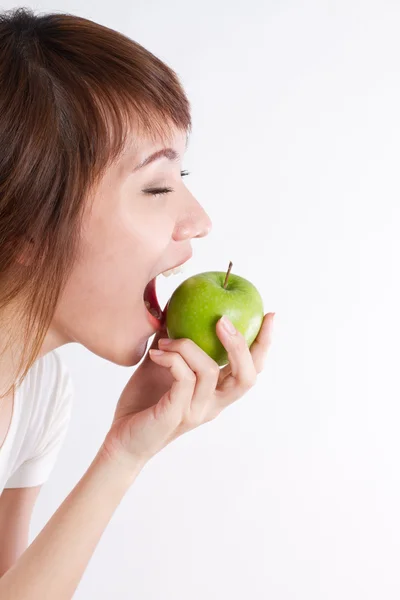Здорова азіатка на кордоні, кусає або їсть зелене яблуко — стокове фото