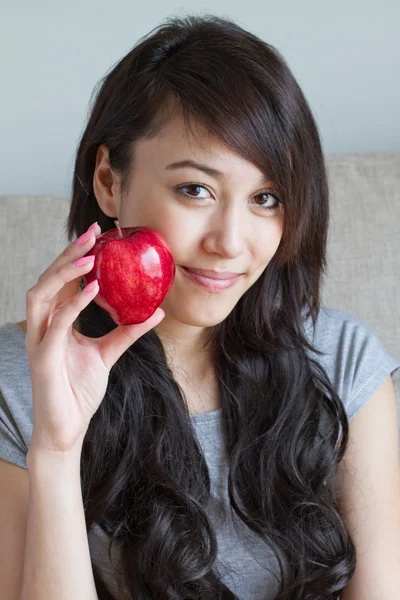 Saludable mujer con rojo manzana, mixta raza asiático caucásico interior —  Fotos de Stock