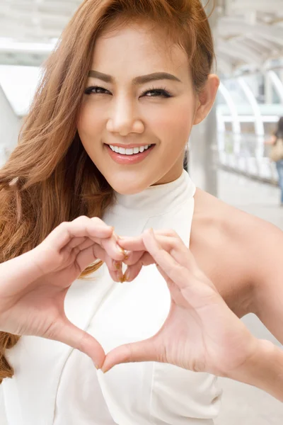 Happy woman showing heart hand sign to you — Stock Photo, Image