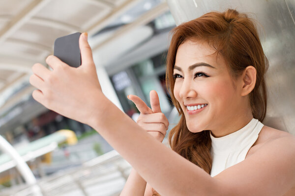 woman taking a selfie with her smartphone, pointing up to the camera