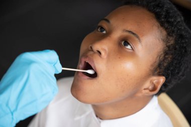 Gırtlak temizleme testi yaptıran Afrikalı kadın; evrensel COVID-19 testi, temas izi, devlet karantinası, sağlık çalışanı riski, tükürük örneğinden tükürük testi