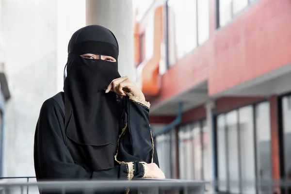 Portrait of thinking Arabian woman covering her face with niqab veil, traditional islamic face mask; concept of social distancing in Muslim culture