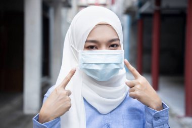 Açık havada yüz maskesi takmayı öneren Müslüman kadın; yeni normal yaşam tarzı kavramı, sosyal uzaklık, eğriyi düzleştirme, grip salgınına karşı önleyici önlem