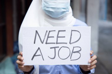 Yüz maskesi takan Müslüman bir kadın, işten çıkarılma nedeniyle parası yok, COVID-19 salgını ekonomik durgunluğa yol açtıktan sonra istihdam kesintisi