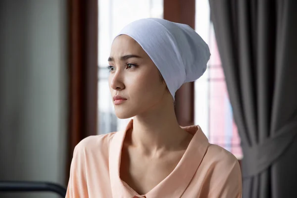 Portrait of sad asian woman cancer patient wearing head scarf after suffering serious hair loss due to chemotherapy