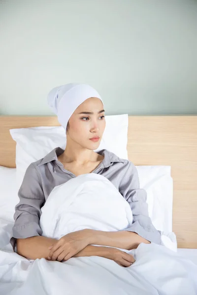 Portrait of sad asian woman cancer patient wearing head scarf after suffering serious hair loss due to chemotherapy