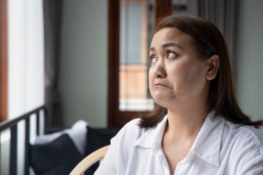 mutsuz Asyalı orta yaşlı kadın yukarı bakıyor.