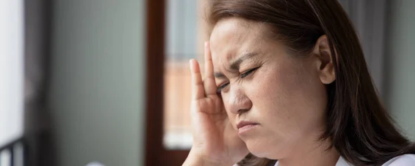 sick asian middle aged woman suffering from headache; health and sickness concept for vertigo symptoms, dizziness, stress, depression, burnout, Alzheimer, brain cancer, Meniere disease, memory loss