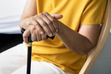 Oturma odasında yalnız oturan üzgün ve yalnız yaşlı bir kadının eli, yalnız emeklilik konsepti ya da huzurevi.