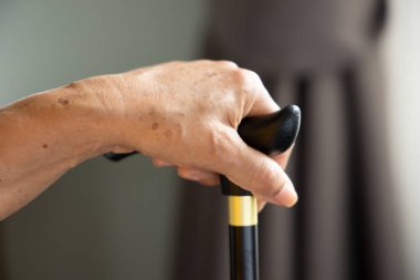 Oturma odasında yalnız oturan üzgün ve yalnız yaşlı bir kadının eli, yalnız emeklilik konsepti ya da huzurevi.