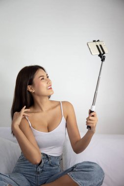 Mutlu kadın akıllı telefonuyla evde video görüşmesi yapıyor; görüntülü konuşma, teletıp, evde çalışma, yeni normal sosyal mesafe önlemi konsepti