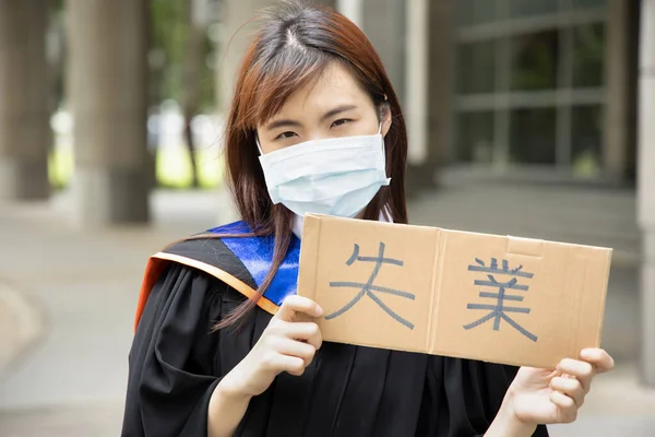 Text in traditional Chinese or Japanese Kanji reads Unemployed, banner carried by college graduate student woman wearing face mask, concept of unemployment, job cut after COVID 19 economic recession