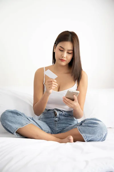 woman shopping at home with smartphone and credit card; concept of video call, shopping at home, tele shopping app or application, telemedicine VDO call, new normal social distancing