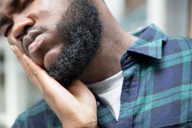 Diş ağrısı olan Afrikalı bir adam; diş ağrısı, diş çürüğü, diş hassasiyeti olan siyah bir adamın portresi; kız ağız sağlığı, diş bakımı konsepti; Afrikalı 20 'li yaşlarda yetişkin erkek modeli