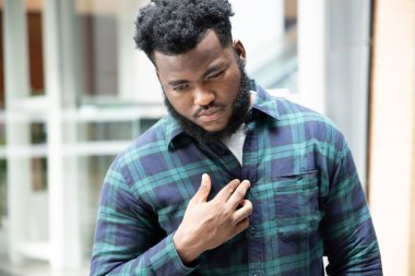 Asit reflüsü veya GERD 'den muzdarip Afrikalı bir adam; hazımsızlık, asit reflüsü veya gerd semptomları olan hasta stresli siyahi bir adam; erkek sağlığı, vücut bakımı, hastalık, ağrı konsepti; yetişkin Afrikalı erkek modeli;