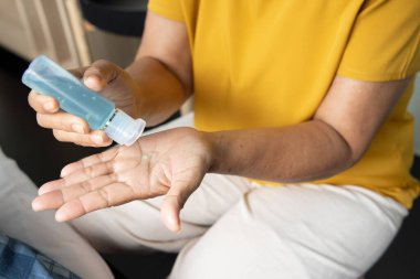 Yaşlı bir kadın elinde alkol jeli dezenfektanı kullanıyor. Yeni normal bir son sınıf öğrencisi. COVID-19 salgınında sağlıklı yaşam tarzına mesafeler koyuyor.