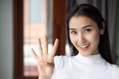Asyalı bir kadın işaret ediyor, dört parmağı sayıyor, mutlu gülümseyen Asyalı bir kadının portresi Çin asıllı yetişkin kadın modelinin 4 ya da 4 puanlık konseptini işaret ediyor.