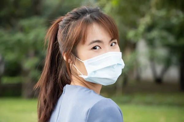 屋外公園で肩越しに顔のマスクを身に着けているアジアの女性 予防措置を取るの概念 社会的距離 コロナウイルス治療を待っている間 新しい通常の生活 Covid 19ワクチン — ストック写真
