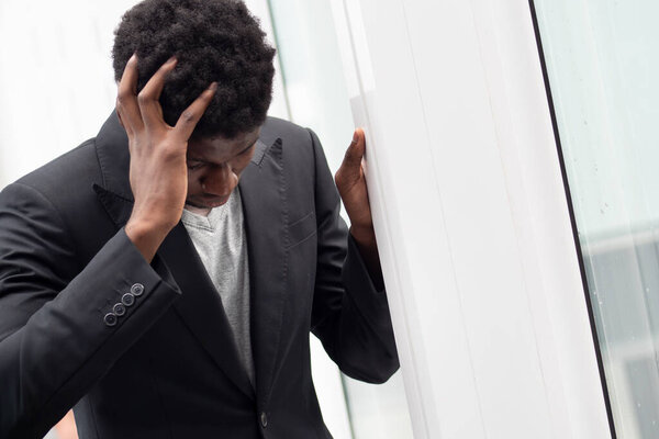 Upset stressed African black businessman having headache, portrait of failed unhappy black business man, concept of work problem, office stress syndrome, economic recession, layoff, unemployment