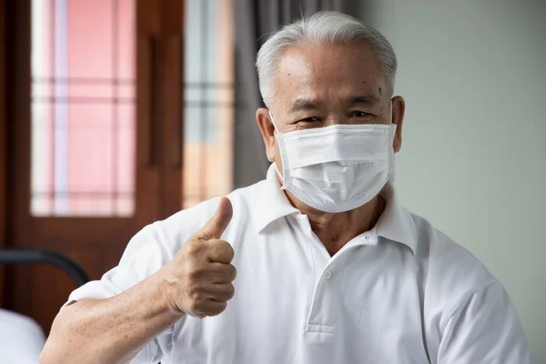 old senior man pointing thumb up for face mask, concept of mouth and nose covering face mask wearing, fine dust pollution, air pollution, COVID-19 contagious disease preventive medicine