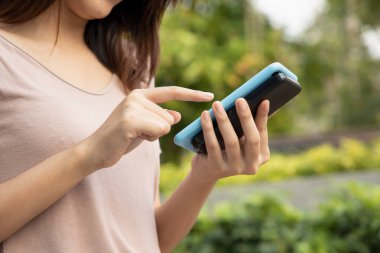 Mutlu Asyalı kadın kablosuz akıllı telefon şarjı kullanıyor, taşınabilir kablosuz indüksiyon güç bankası pili cihazı.