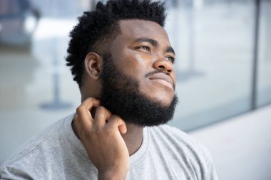 Kaşınan boyun derisinden muzdarip bir adam; alerji, isilik, mantar, tinea problemi, cilt bakımı, cilt bakımı, dermatoloji konsepti, yetişkin siyahi Afrikalı erkek modeli ile derisini kaşıyan hasta Afrikalı bir adam.