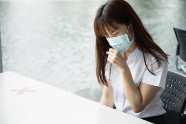 Hasta, aşılanmış Asyalı kadın değil. Öksürük, COVID-19 koronavirüs belirtileri gösteren maske takıyor.