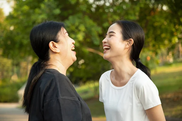 Happy senior mother talking and laughing with asian young adult daughter in the park, healthy body and mind lifestyle, family togetherness, mother and daughter, mother day concept