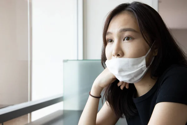 young Asian woman improperly wearing face mask, concept of wearing face mask in wrong way, ignoring precaution measure, social distancing lifestyle while waiting for coronavirus cure, COVID-19 vaccine