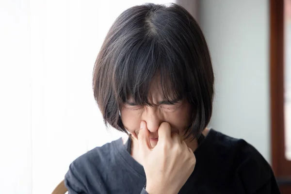 asian woman covering her nose for bad smell, concept of stink construction paint, bad breath, unpleasant smell, rotten food, odor, body bad smell, air pollution, polluted air
