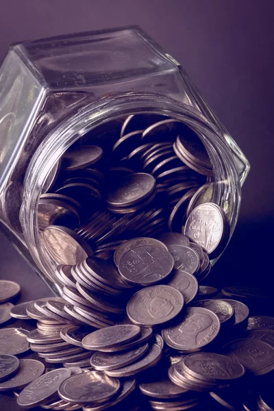 Coins spilling out of a glass bottle with filter effect retro vi