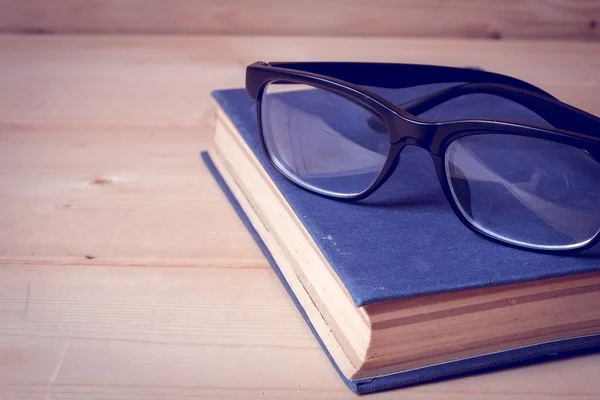 หนังสือเก่าและแว่นตาบนโต๊ะไม้ที่มีผลการกรองย้อนหลัง — ภาพถ่ายสต็อก