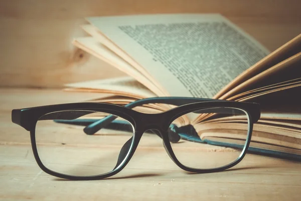 Старые книги и очки на деревянном столе с эффектом фильтра ретро — стоковое фото