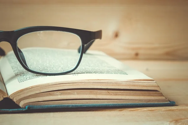 Старые книги и очки на деревянном столе с эффектом фильтра ретро — стоковое фото