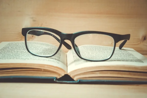 Vecchi libri e bicchieri su un tavolo di legno con effetto filtro retrò — Foto Stock