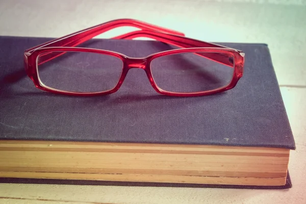 Старые книги и очки на деревянном столе с эффектом фильтра в стиле ретро — стоковое фото