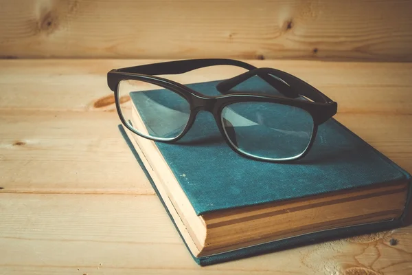 Stare książki i okulary na drewnianym stole z filtr efektu retro — Zdjęcie stockowe