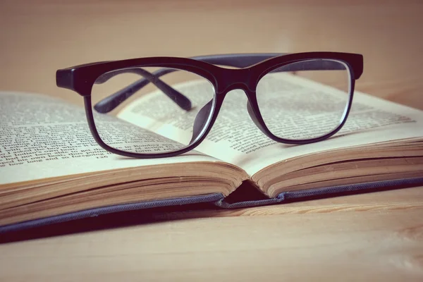 Oude boeken en glazen op een houten tafel met filtereffect retro — Stockfoto