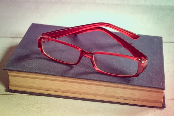 Livros antigos e óculos em uma mesa de madeira com efeito de filtro estilo vintage retro — Fotografia de Stock