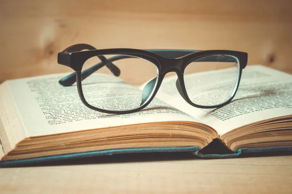 Stare książki i okulary na drewnianym stole z filtr efektu retro — Zdjęcie stockowe