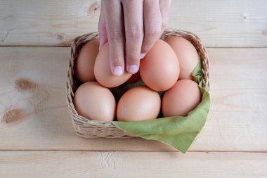 Ahşap arka planda yumurta tutan el. 