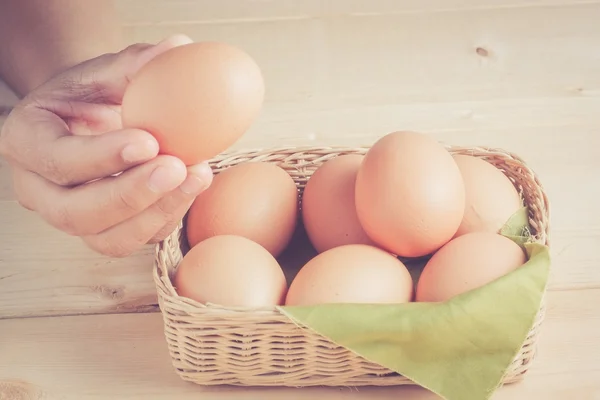 Hand holding egg on wooden background with filter effect retro v Stock Image