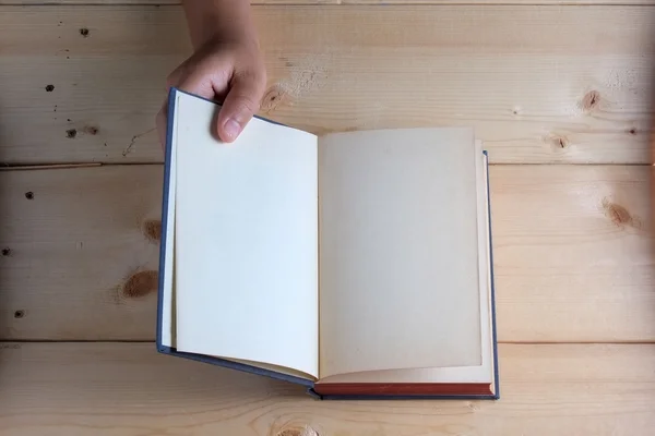 Hands hold book on wood table — Stock Photo, Image