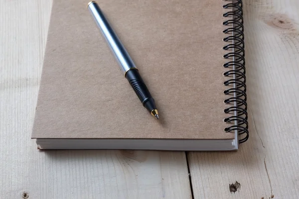 Ручка и книга на деревянном фоне — стоковое фото