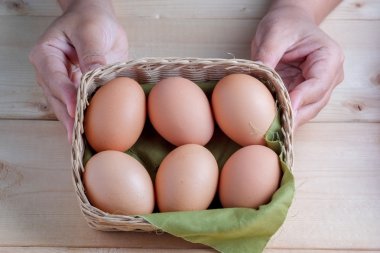 Ahşap arka planda yumurta tutan el. 