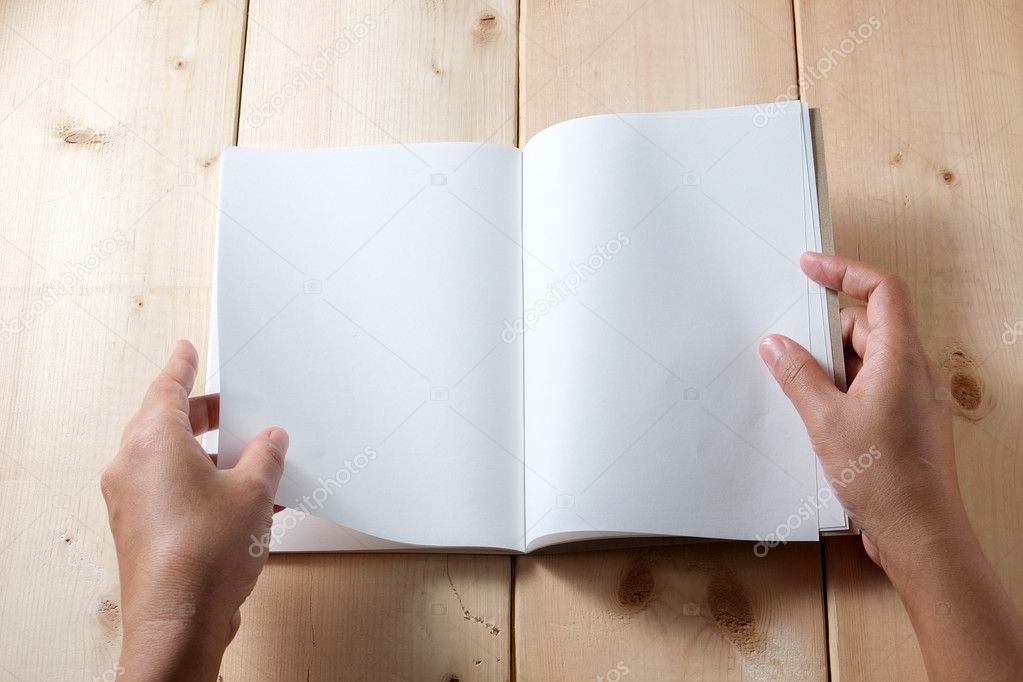 Hands hold book on wood table