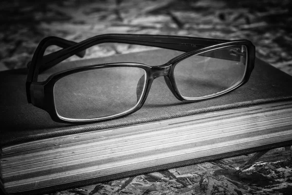 Черно-белые очки и книга — стоковое фото