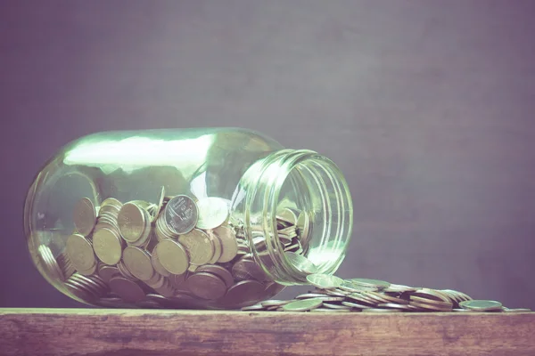 Monedas derramadas de una botella de vidrio con efecto de filtro estilo retro vintage —  Fotos de Stock