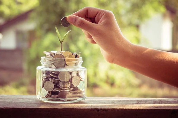 Mano poner monedas de dinero con efecto de filtro estilo vintage retro — Foto de Stock